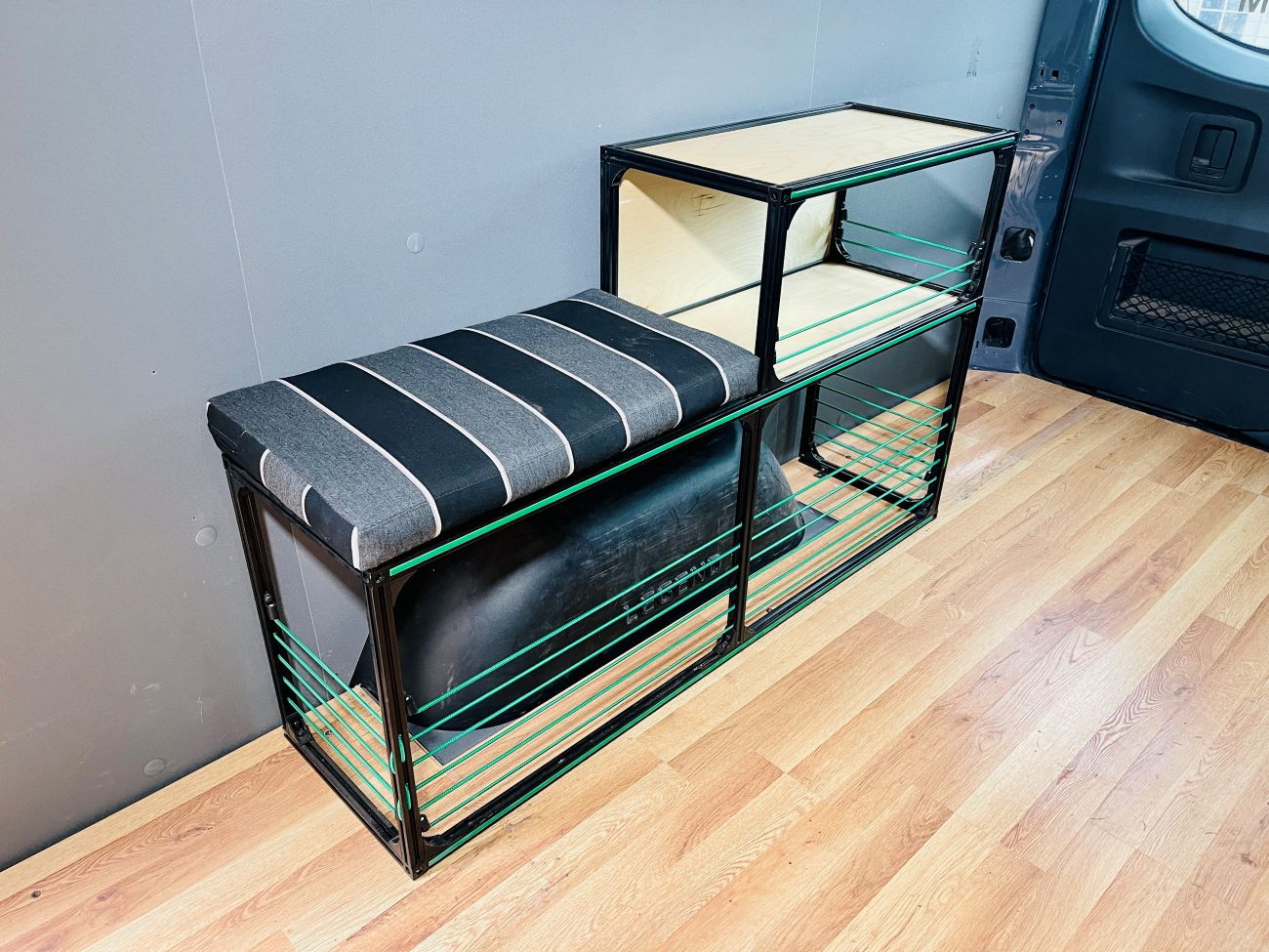 camper van wheel well bench and shelving with black cushion