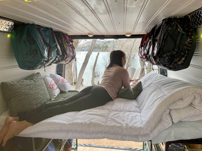 camper van diy bed kit in conversion van reading a book looking at the lake