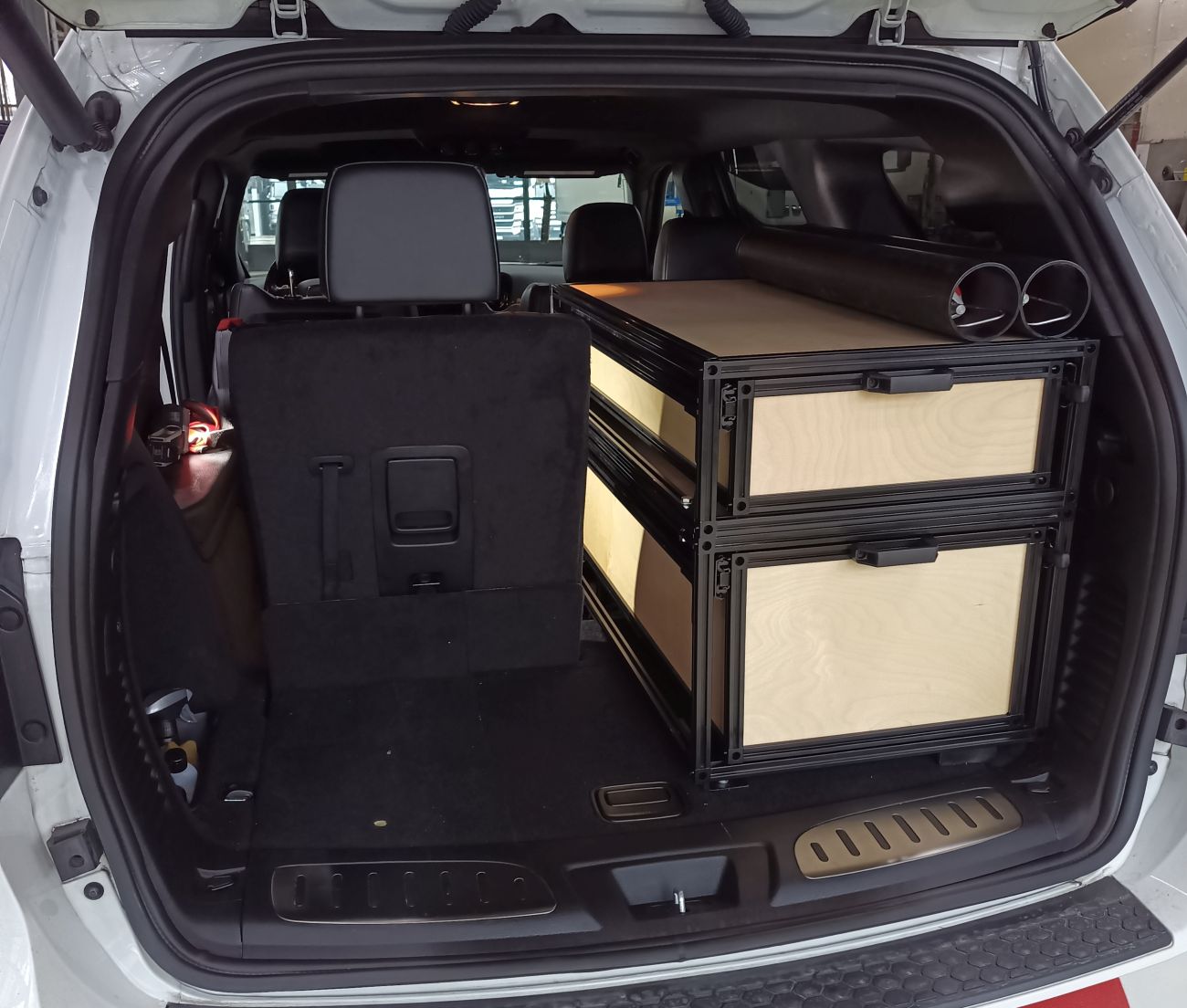 Trunk of a suv with storage drawers and a black seat
