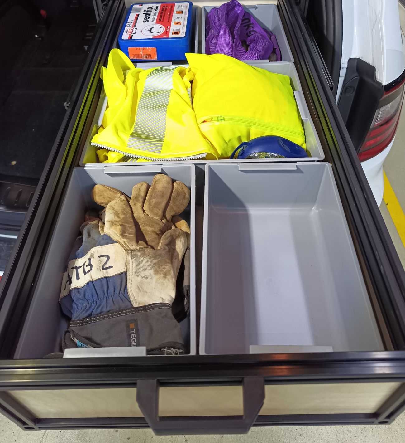 suv rear cargo drawer with safety gear including gloves and reflective vests.