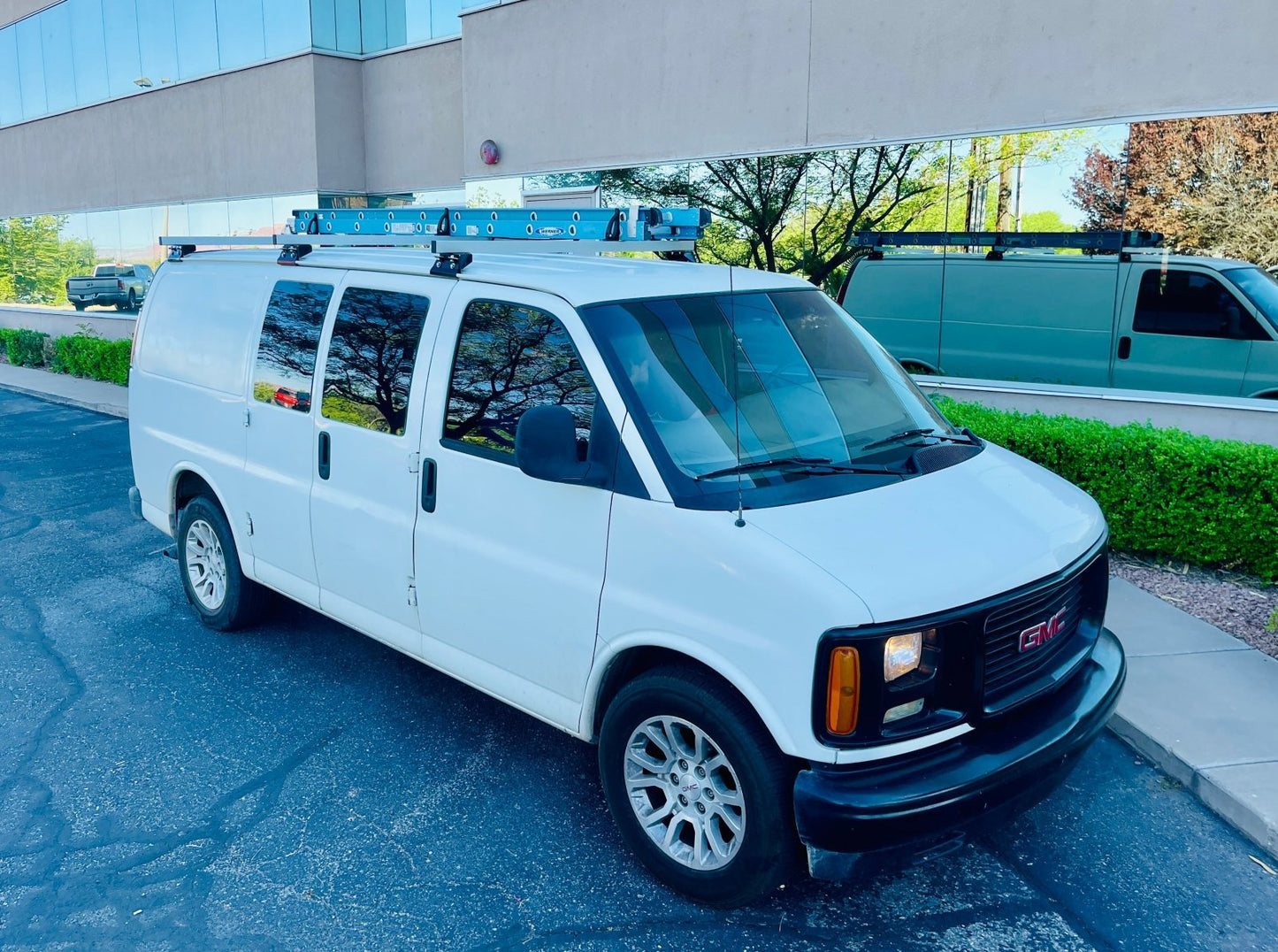 van roof rack on a chevy express with a mounted werner ladder on top